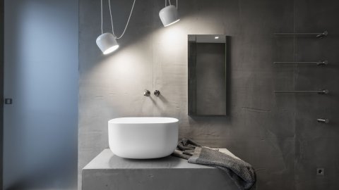 Hohe WT-Schale aus Corian auf Möbel in Beton-Optik, Spiegelschrank, Armaturen Edelstahl, Pendelleuchten, Spiegelschrank, Handtuch-Wärmekörper, Schiebetür