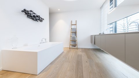 Freistehende Badewanne aus mattweißem Corian, Wandkunst Fische, Handtuchleiter aus Holz, hängender Waschtisch mit Doppelbecken, Waschtisch vor Fenster, Vorhang, Hängender Spiegel beleuchtet